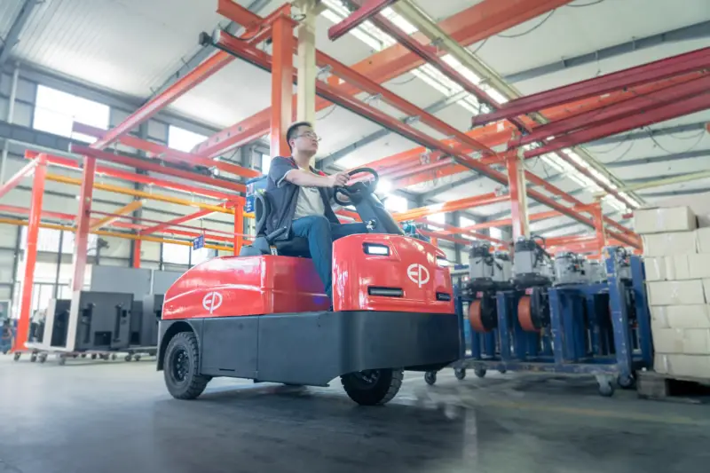 Người lái xe kéo điện EP QDD601T di chuyển hàng hóa trong kho rộng