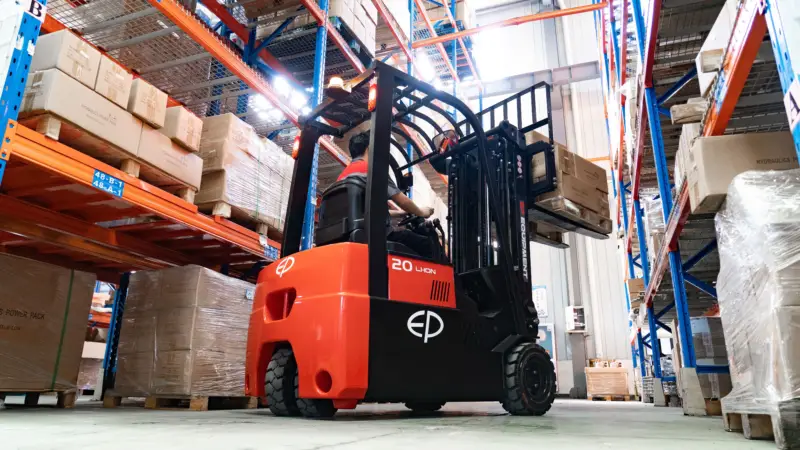 Xe nâng điện TVL181 đang di chuyển trong kho, nâng hàng lên kệ cao